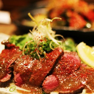 Kobe beef carpaccio with special sause on the dish.