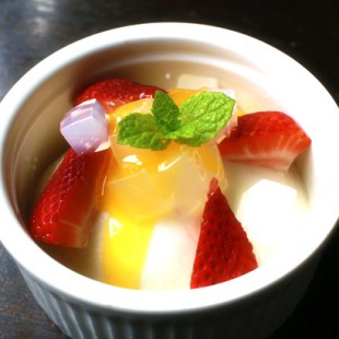 A big cup of Annin-Tofu with some slices of fruits and mint leaves